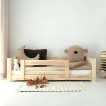 Kinderbett im Kinderzimmer mit hellem Teppich und Montessori-Spielzeug Kinderbett im Kinderzimmer mit hellem Teppich und Montessori-Spielzeug