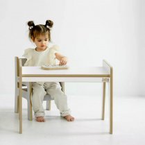 Weißer Kindertisch und Stuhl, Mädchen sitzt und liest ein Bilderbuch.