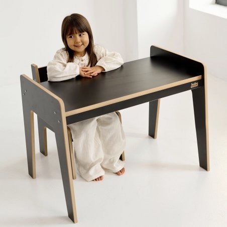 Schwarzer Tisch und Stuhl aus Holz, fröhliches Kind beim Spielen. Schwarzer Tisch und Stuhl aus Holz, fröhliches Kind beim Spielen.