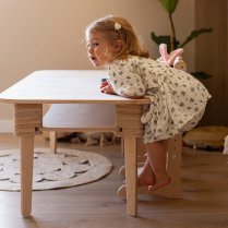 Mädchen spielt am höhenverstellbaren Kindertisch aus Holz