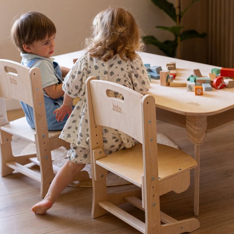 Kinder spielen am Tisch im Kinderzimmer – verstellbare Holzstühle