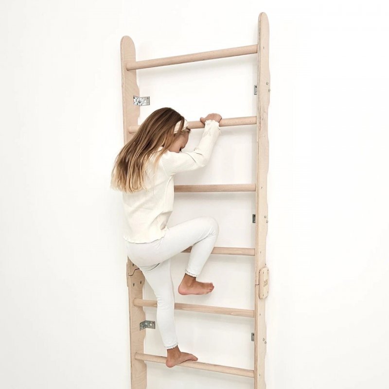 Mädchen klettert an der Sprossenwand im Kinderzimmer