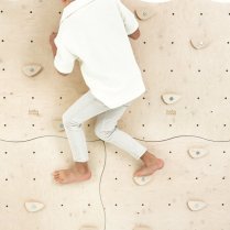 Junge klettert an Kletterwand aus vier verbundenen Modulen im Kinderzimmer Junge klettert an Kletterwand aus vier verbundenen Modulen im Kinderzimmer